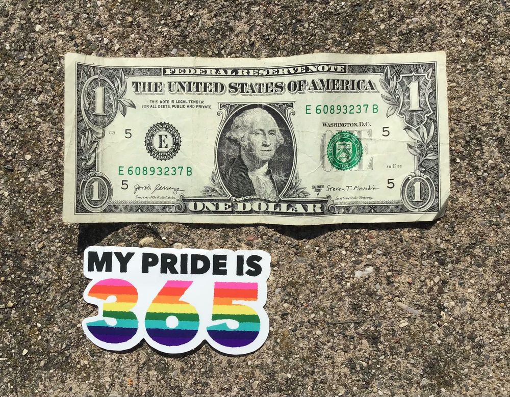 The same sticker as before, now compared to a US $1 bill. The sticker is about half as long as the bill and a bit shorter than the bill.