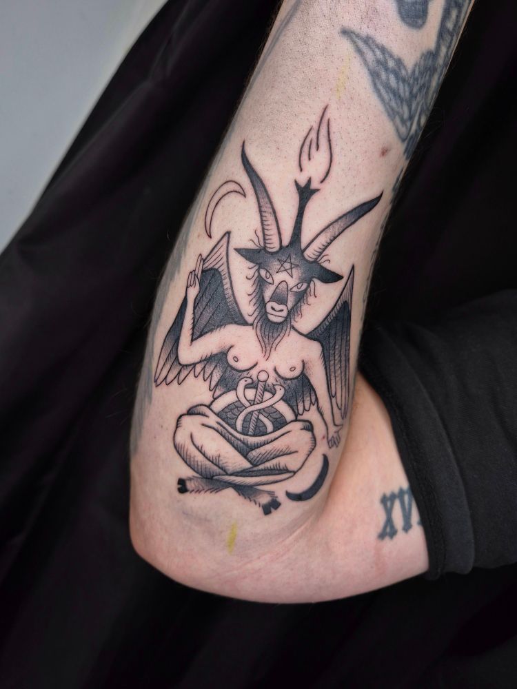 A black ink tattoo of the demon baphomet on the forearm 