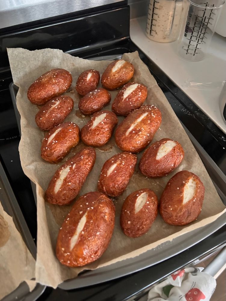 a baking tray of 15 ill-split pretzel rolls, sprinkled with salt