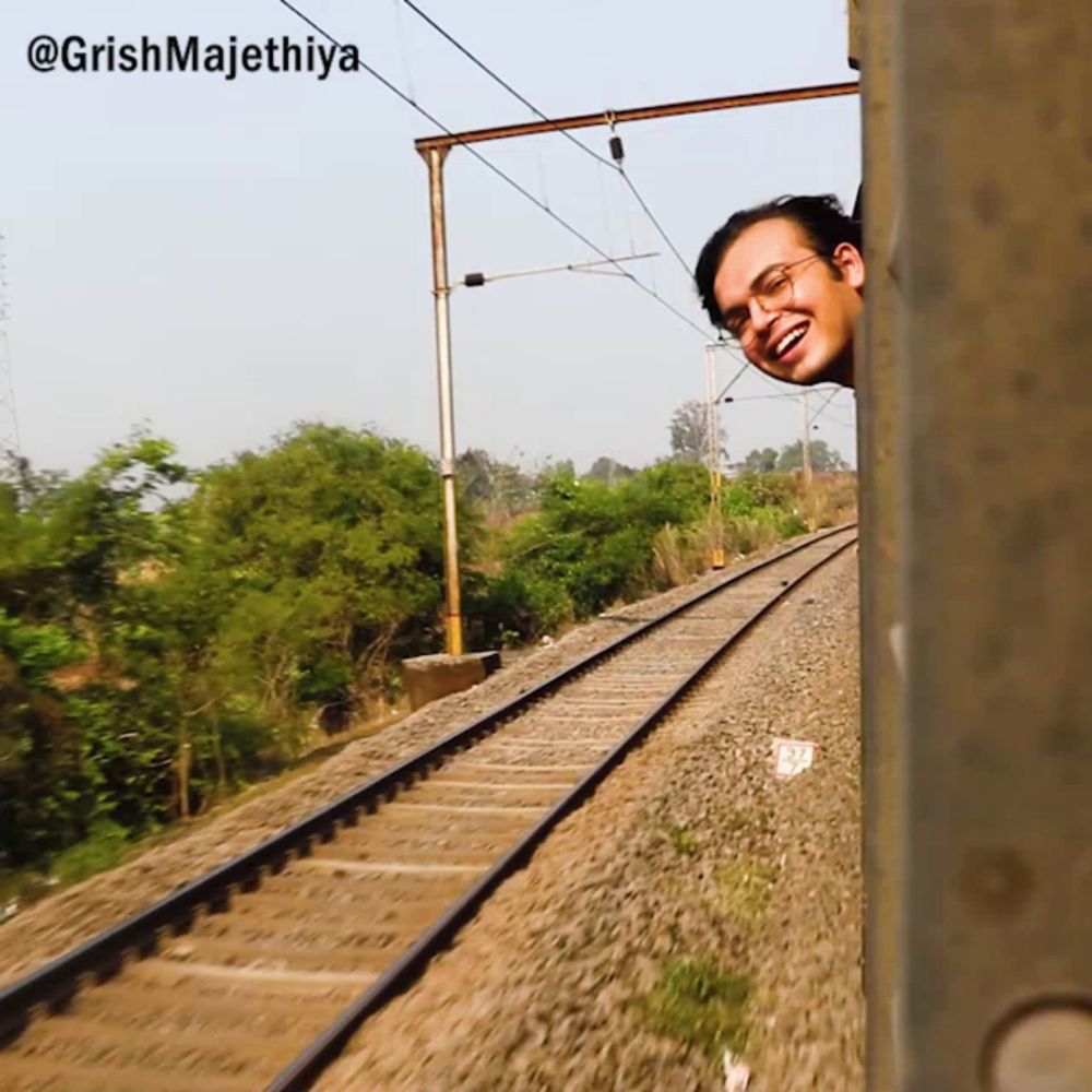 a man peeking out of a train window with the caption @grishmajethiya