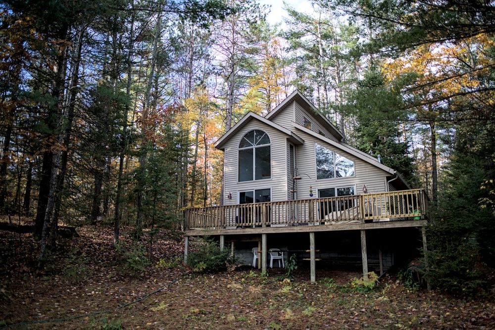 A cozy cottage with large windows and a wraparound deck sits nestled in a pine and hardwood forest. Golden fall leaves provide a warm contrast to the cool tones of the evergreens.

Camera & Processing Details:
Photos taken with a Sony a7RII using a Minolta 28mm F2.8 MD W.Rokkor-X lens.
Images were processed in Darktable.