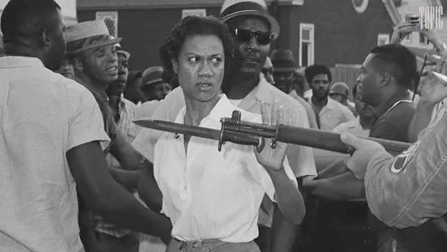 Gloria Richardson in 1964 side-eyes a white National Guardsman as she pushes his bayonet away with her hand and walks past