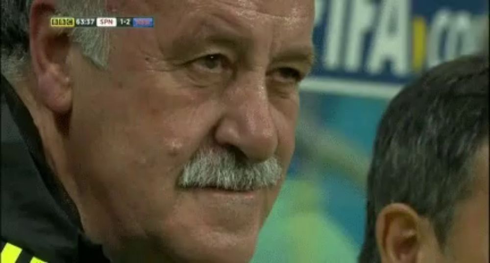 a man with a mustache is watching a soccer game and the score is 1-2