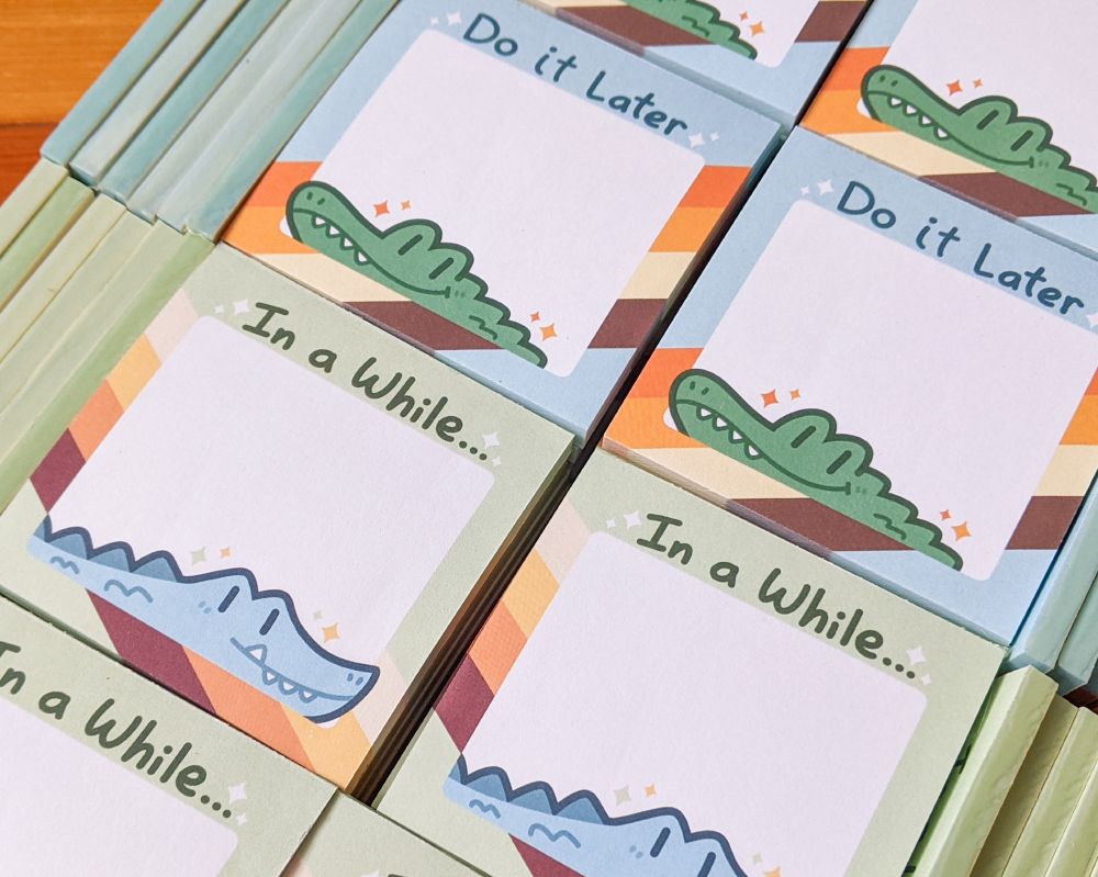 Photo of stacks of memo pads.  One design features an alligator with the text "Do it Later" and the other features a crocodile with the text "In a While..."