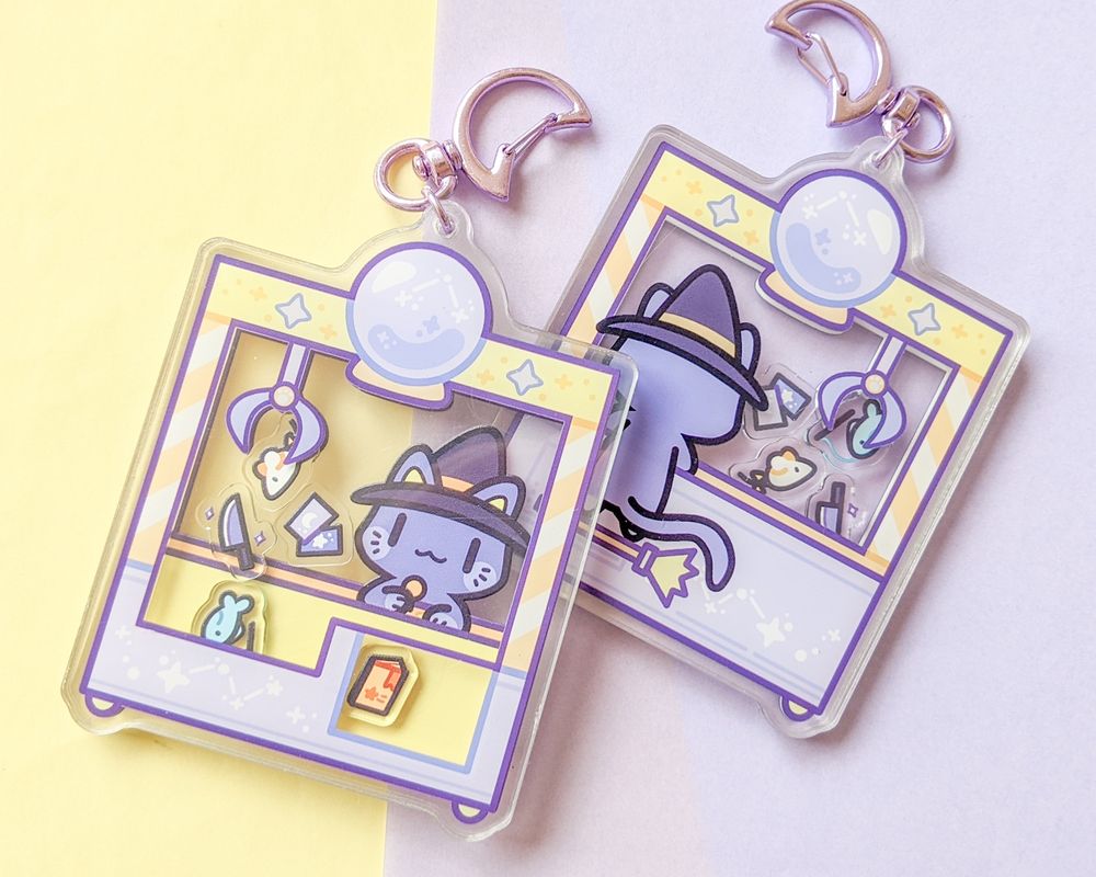 Photo of a shaker charm.  The design is a witchy cat at a UFO catcher