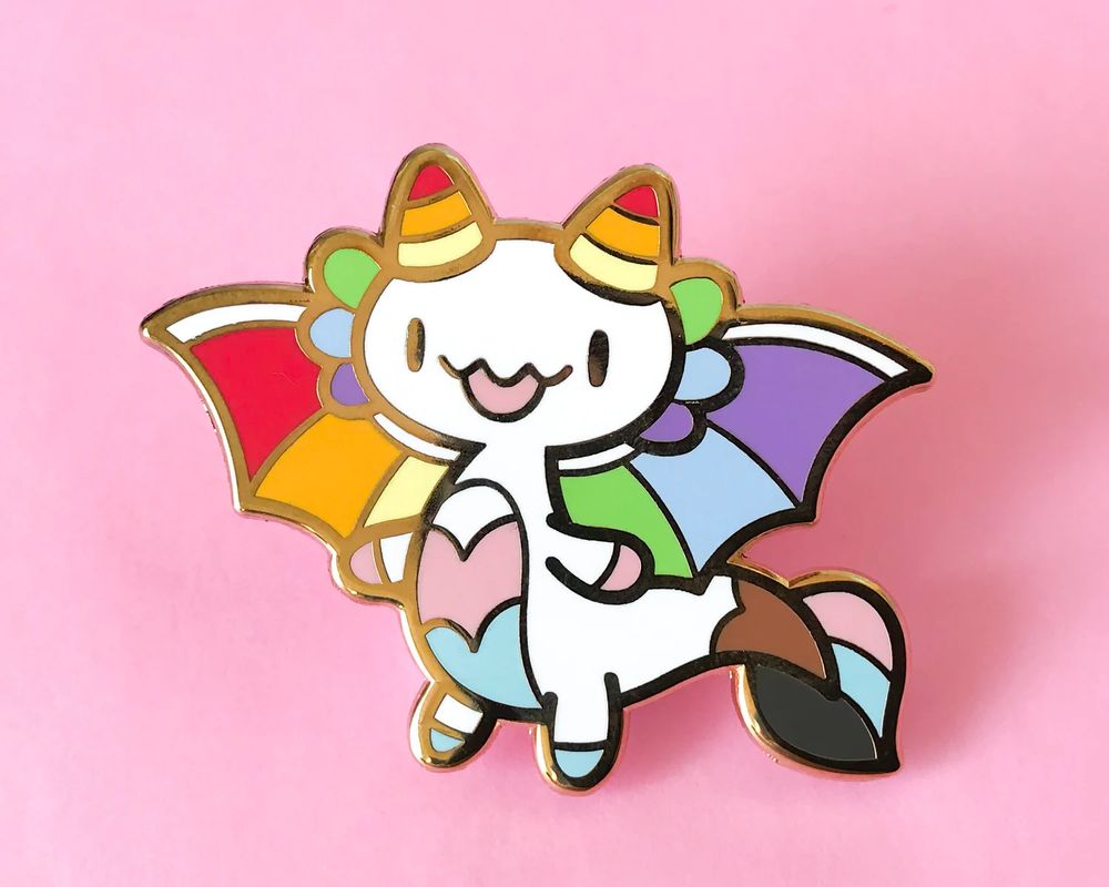 Photo of my Progress Pride Dragon enamel pin design on a pink background