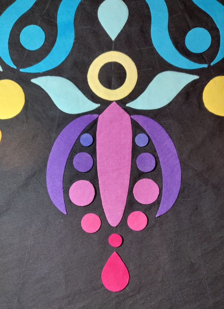 A series of colorful applique shapes placed to resemble an abstract flower.