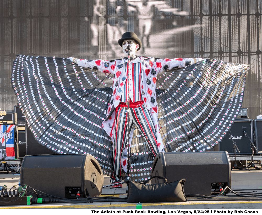 The Adicts at Punk Rock Bowling, Las Vegas 5/24/25 | Photo by Rob Coons

Singer of the Adicts wearing full on clown attire and a top hat while spreading a fan cape type thing. 
