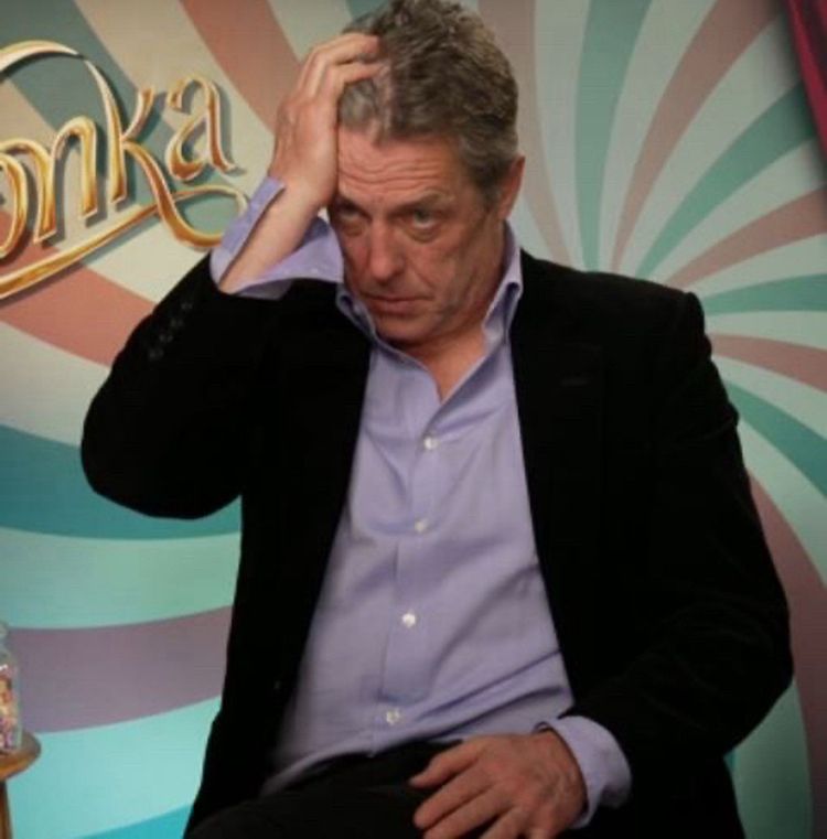 Photo d’une interview de Hugh Grant pendant la promo de Wonka, il se passe la main dans les cheveux et a l’air au bout du rouleau.