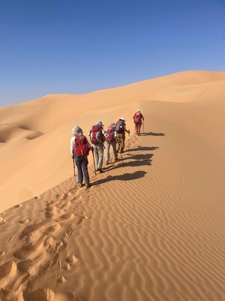 Une file de marcheurs sur une dune dans le désert . Il créent une trace qui disparaîtra vite