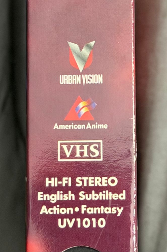 Spine of a vhs tape, showing the urban vision and American anime logos. The American anime logo is a triangle with a little squiggly thing on top.