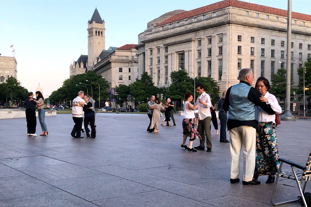 Couples dancing in a plaza with federal buildings in the background 