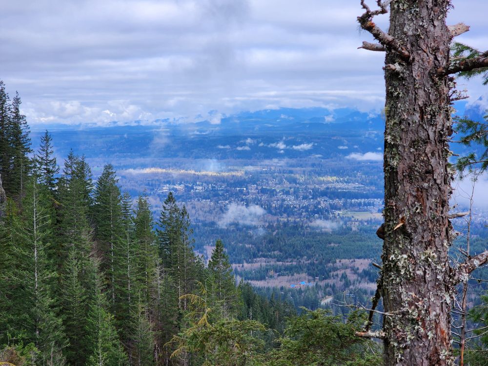 Telephoto shot of a town in the distance, hedge in by sloping treeline and mountains