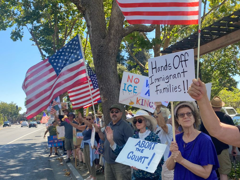 American flags and a protest sign that says Abort the Court