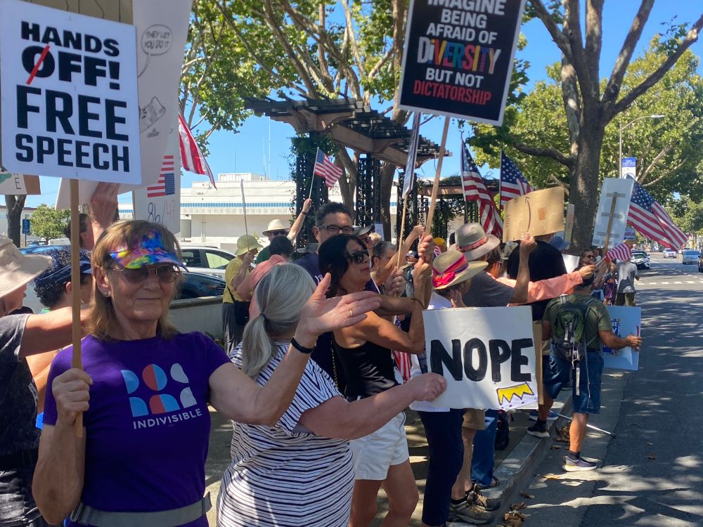 A protest sign that says Nope with an upside down crown. And Hands off free speech 