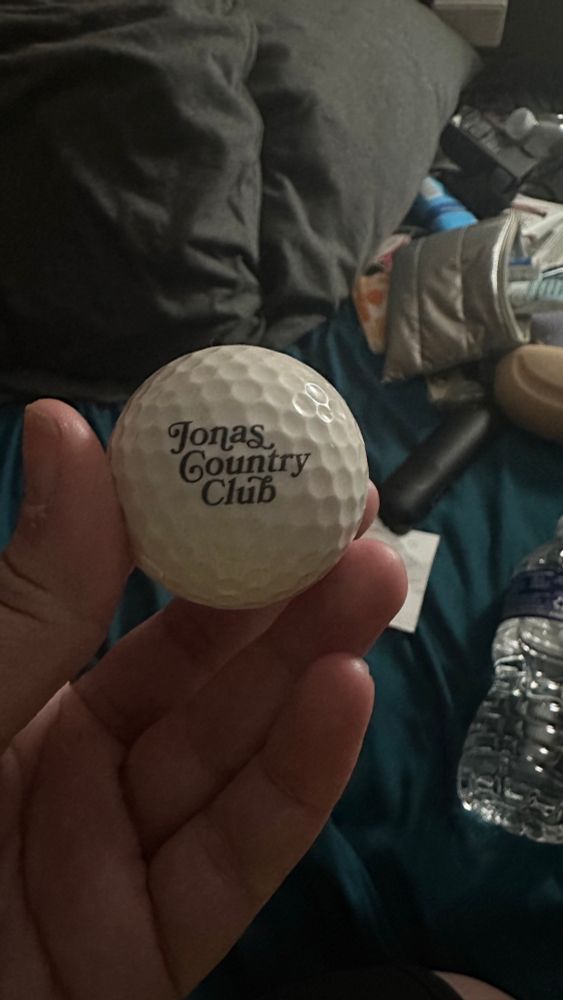 a white golf ball with “jonas country club” written on it in black