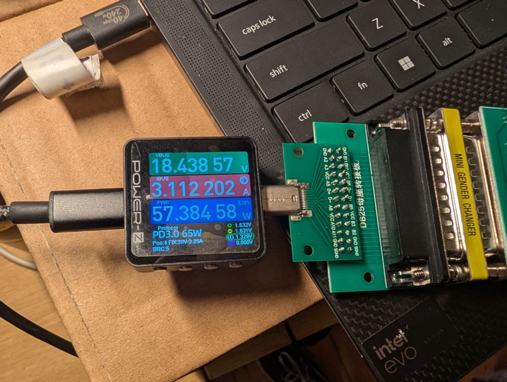 A USB power meter showing 18.4V, 3.1A, 57.4W running through the aforementioned cursed mess of adapters 