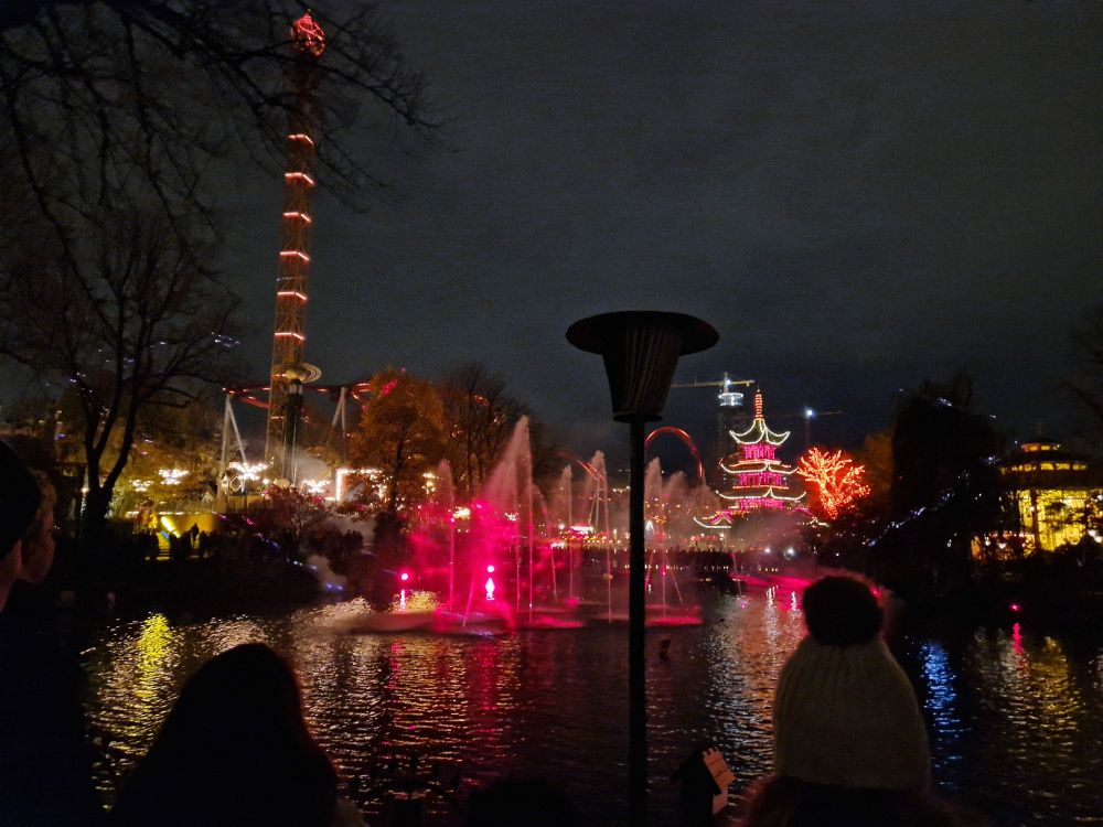 Bright lights and fountains during a nighttime illuminations show on the lake in Tivoli Gardens in Copenhagen, Denmark.