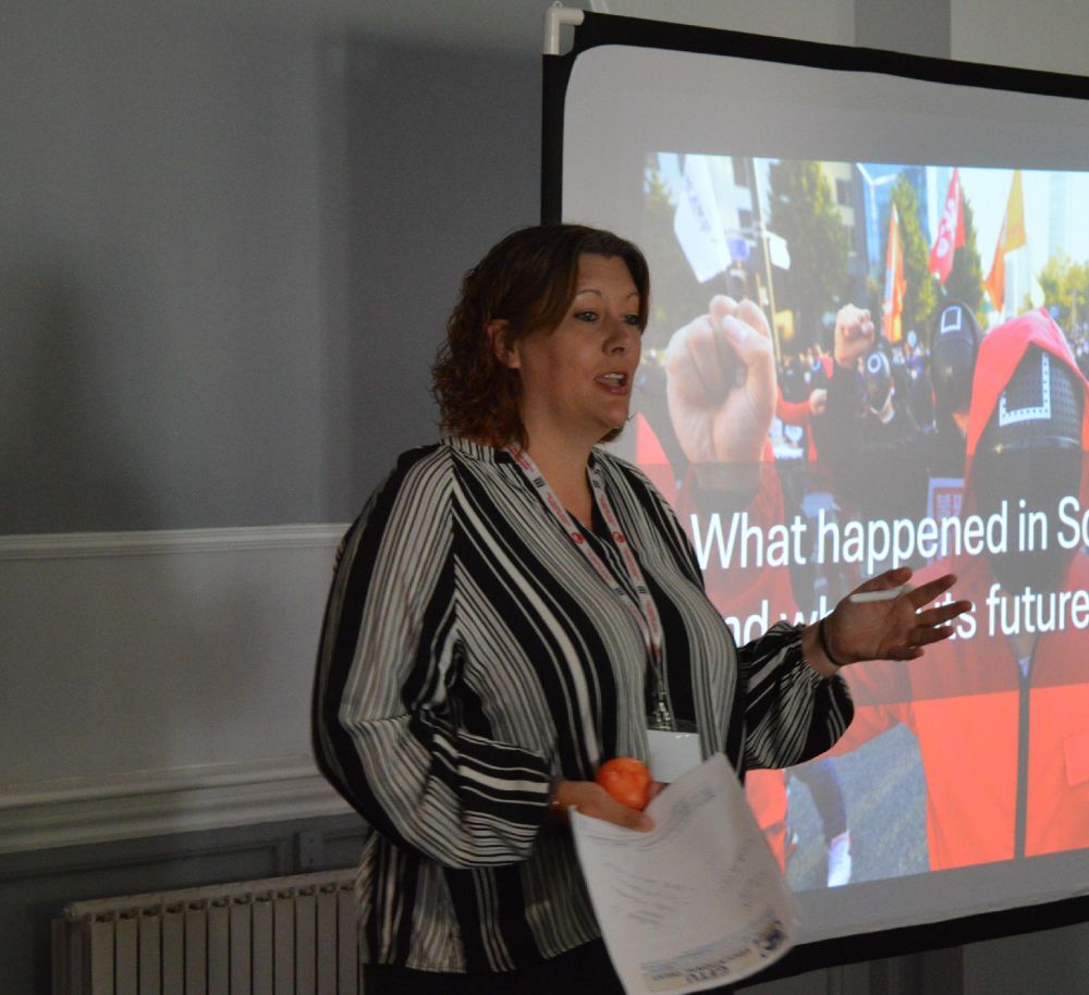 A person presenting a lecture with a PowerPoint slide in the background. 