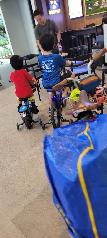 Two kids with their backs to me on bicycles, with my own bike in the foreground
