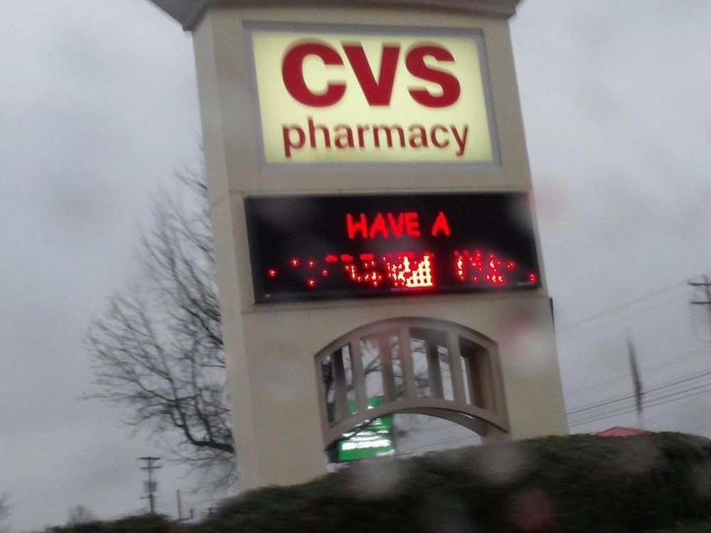 photo of CVS sign against overcast sky with black marquee and text in red reading:

HAVE A
[glitched out]