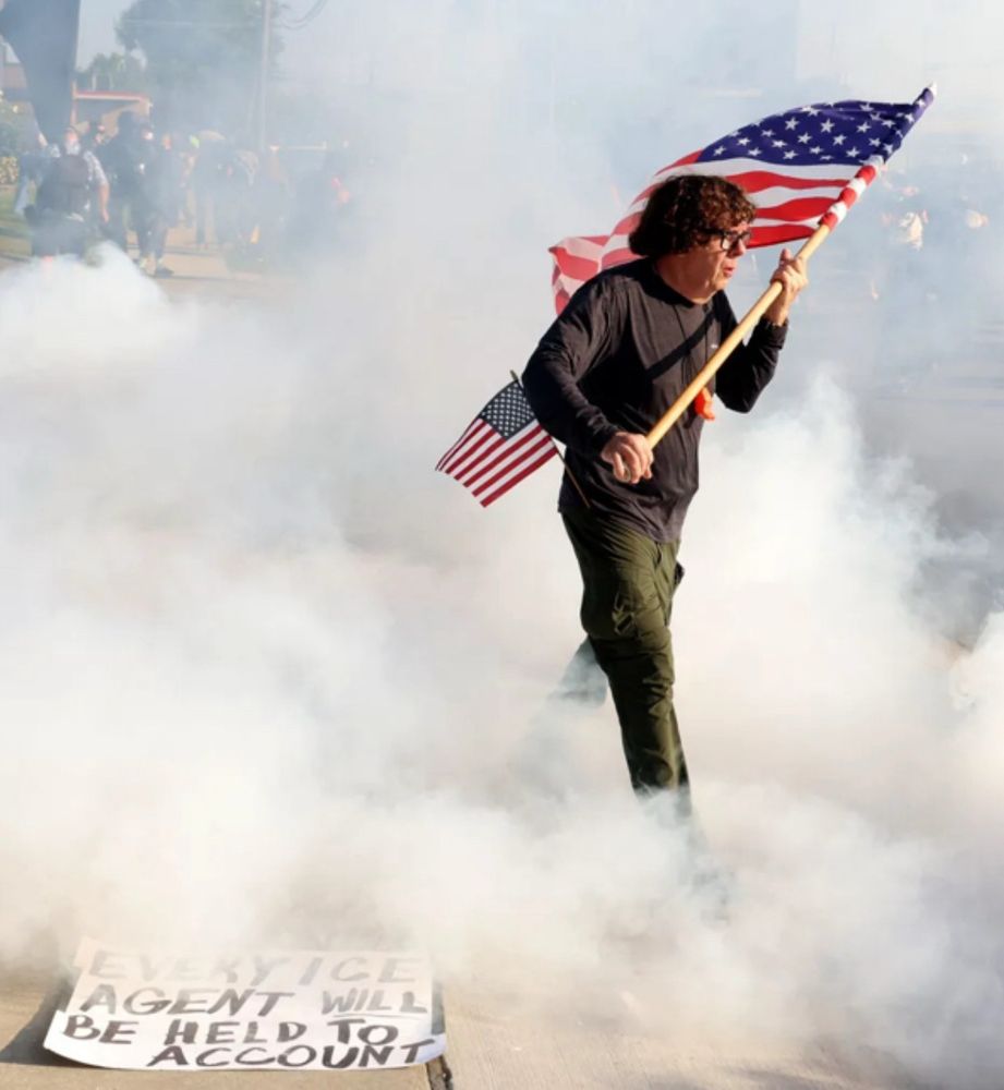 An walking through smoke carrying US flag. Chicago tribune photograph. The man was a Marine in the 1980s.