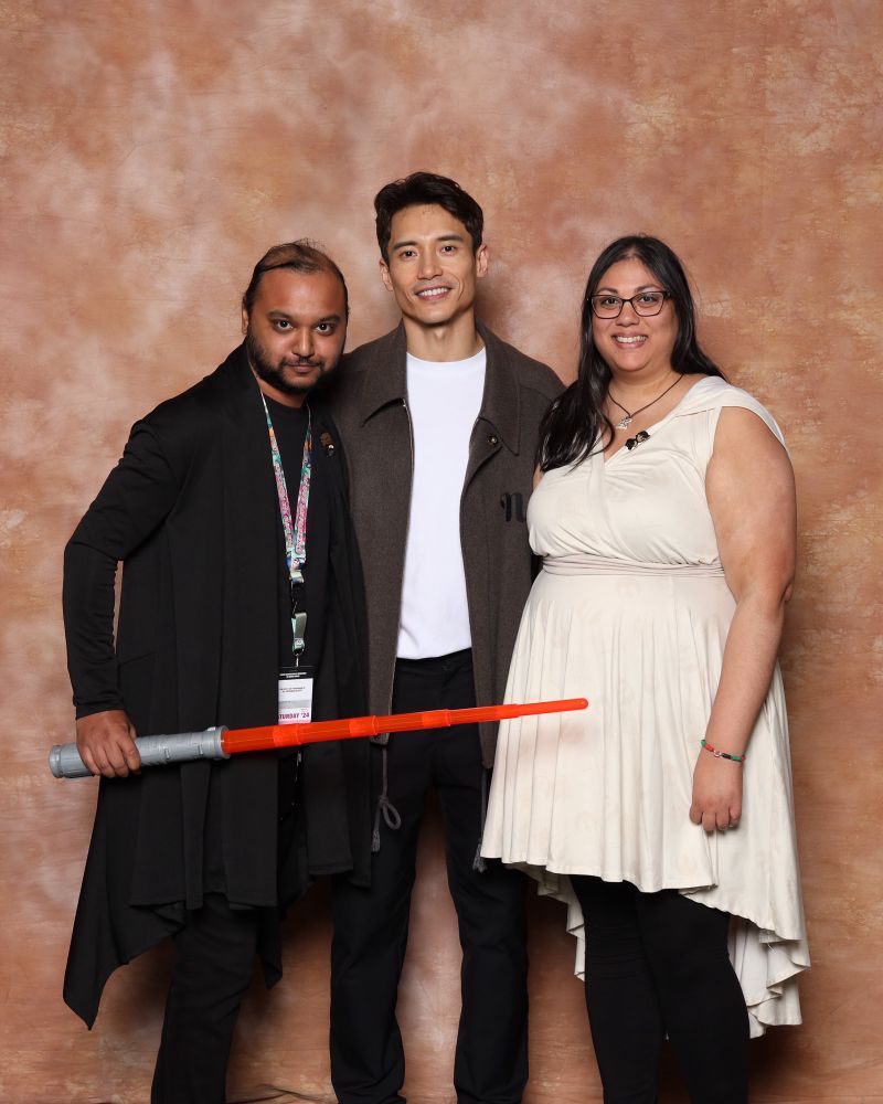 Me and my husband in a photo op with Manny Jacinto. Husband is holding a lightsaber. Photo is from San Francisco Fan Expo. 