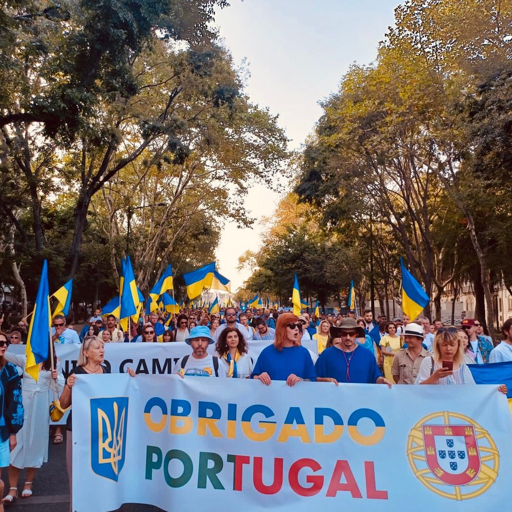 Marcha de pessoas com bandeiras ucranianas e um banner a dizer "Obrigado Portugal" com os brasões da Ucrânia e de Portugal na Avenida da Liberdade, em Lisboa.
