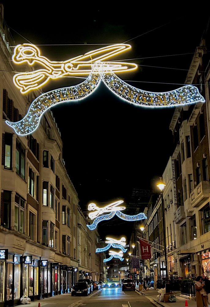 Christmas lights repeat periodically along Saville Row and are shaped into a pairs of scissors cutting a ribbon 