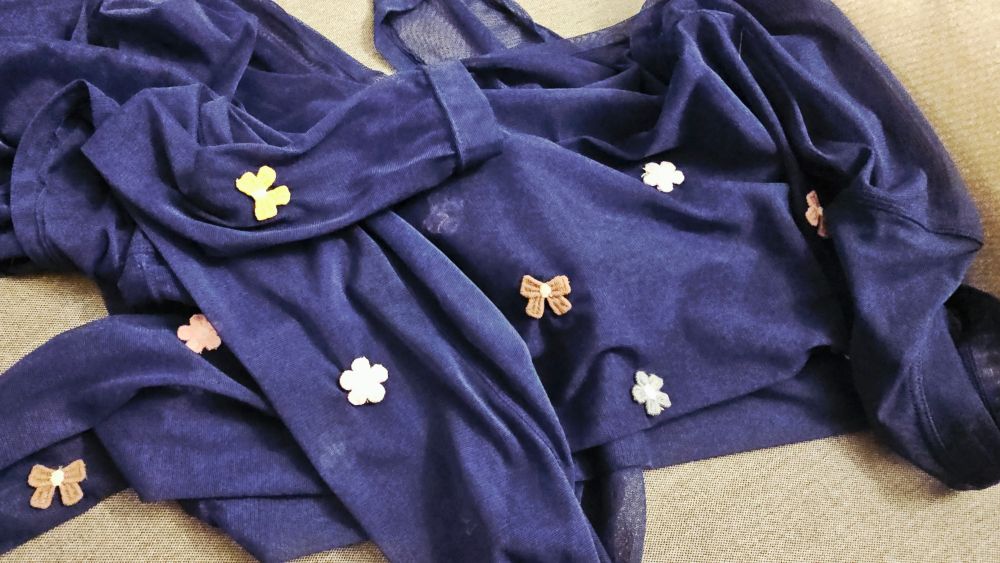 Small pastel flowers on a dark blue mesh top. There are a good number and I sewed them all on by hand and now my hands hurt 
