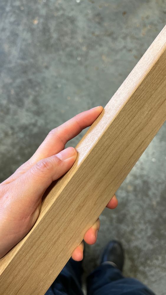 Hand holding a piece of wood with rounded edges