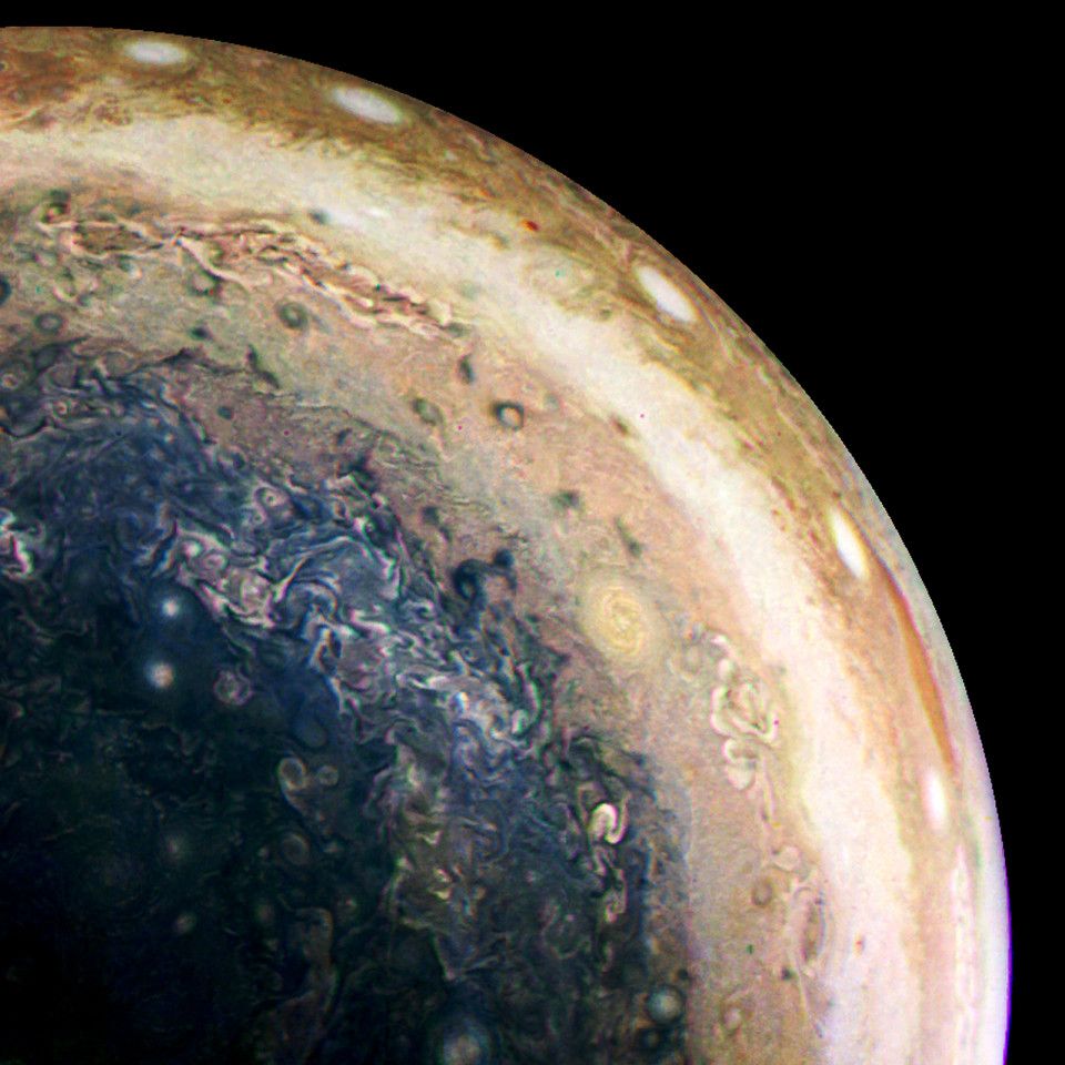 Wide view of Jupiter's southern hemisphere, including the polar area. A set of five bright round storms is present closer to the equator, and turbulent cloud systems are distributed throughout.