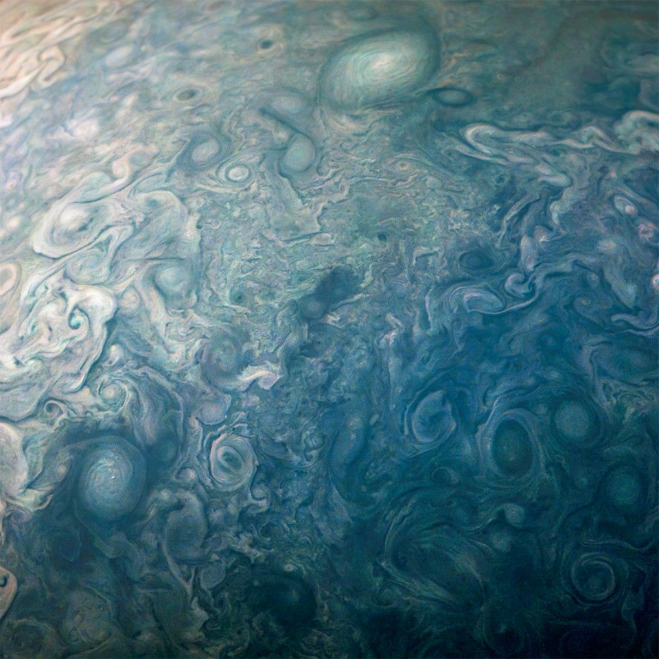 Photo of the region nearby one of Jupiter's poles, displaying a unique blue-green colouration very rare on the planet. Many cyclones and anticyclones can be seen spread throughout, as well as a lot of turbulent flow everywhere in frame.