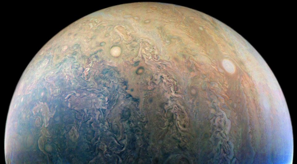 Wide-angle view of one of Jupiter's subtropical regions. The polar region can be distinguished by its unique colouration, and countless swirly and oval storms are shown throughout the whole view.