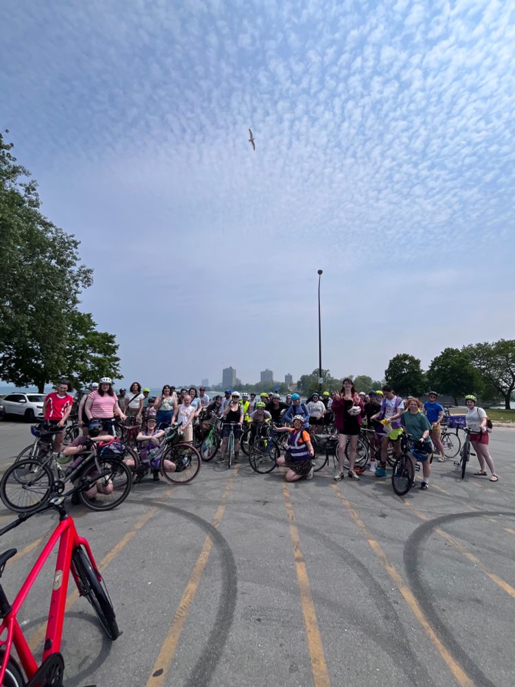 a group of f+t bike riders in a parking lot smiling with their bikes 