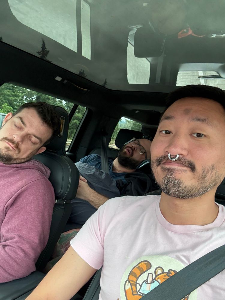 3 men in a car; two of them are dozing peacefully. 
