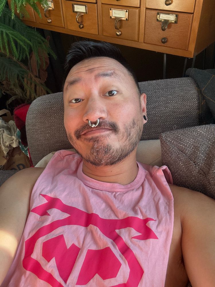 A selfie: me, reclining on a couch, wearing a pink shirt. 