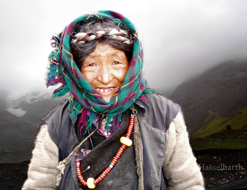 Tibetan elder wearing green scarf, jacket and red beads