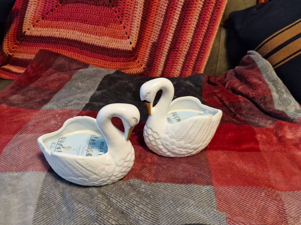 Two ceramic swans on a sofa