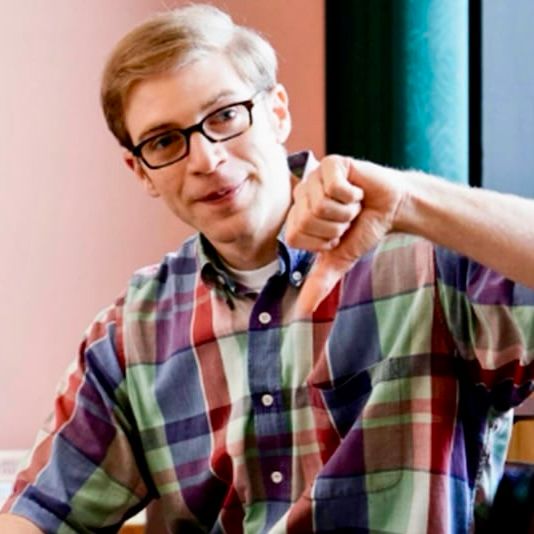 writer-actor-comedian Joe Pera smiling pleasantly while making a disapproving “thumbs down” gesture