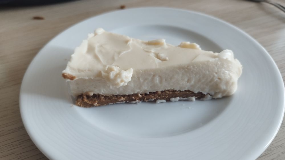 part de cheesecake végane dans une assiette. Une base de spéculoos pour le fond de tarte