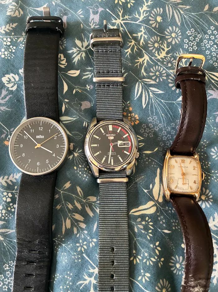 Three watches. A black Braun. A black, red and silver Seiko 5 automatic. A gold and white 1940s Hamilton.