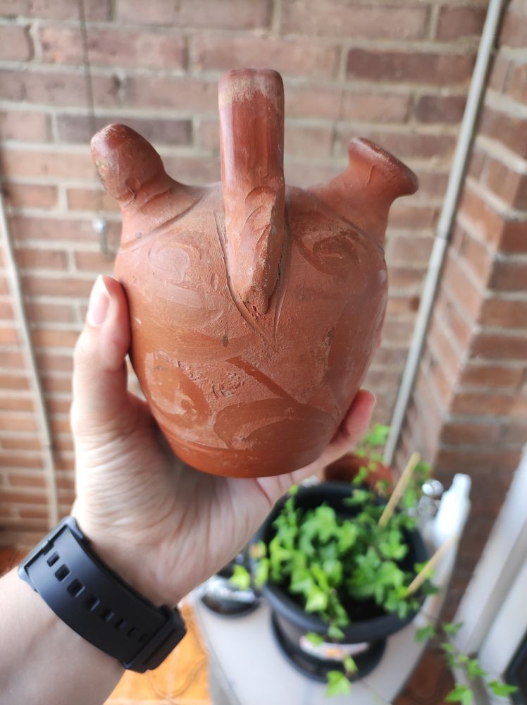 Botijo de barro muy pequeño, lo puedo coger con una mano, y de fondo pared de ladrillos. 