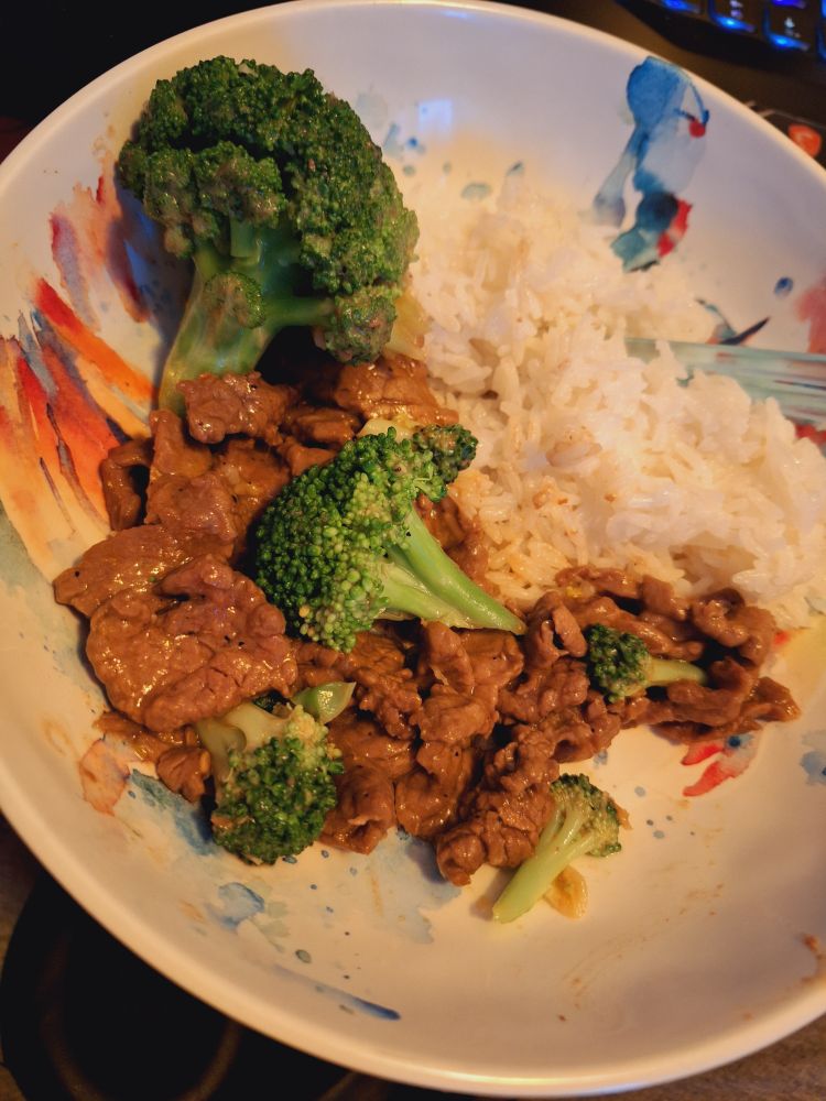 a bowl of beef and broccoli with a side of jasmine rice