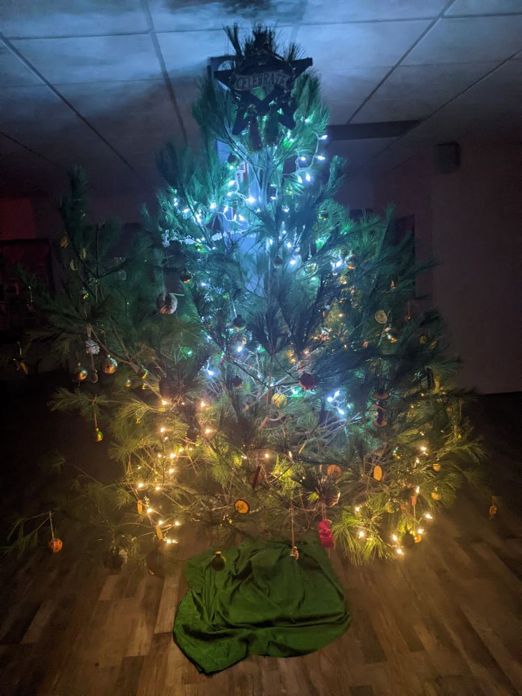 a natural pine tree lit and decorated for Yule