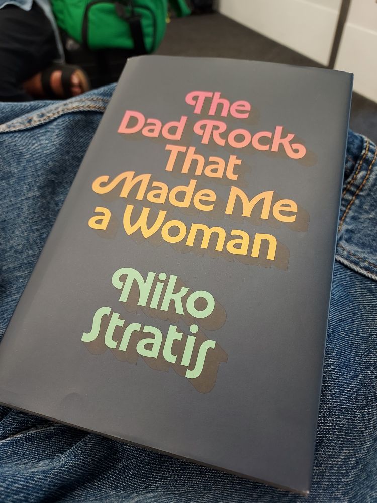 A copy of the book The Dad Rock That Made Me A. Woman by Niko Stratis.