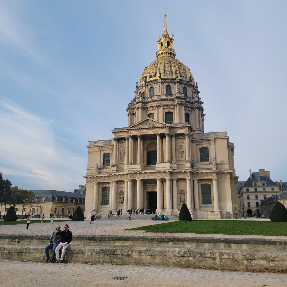 A photo of two men sitting in front of Les Invalides.