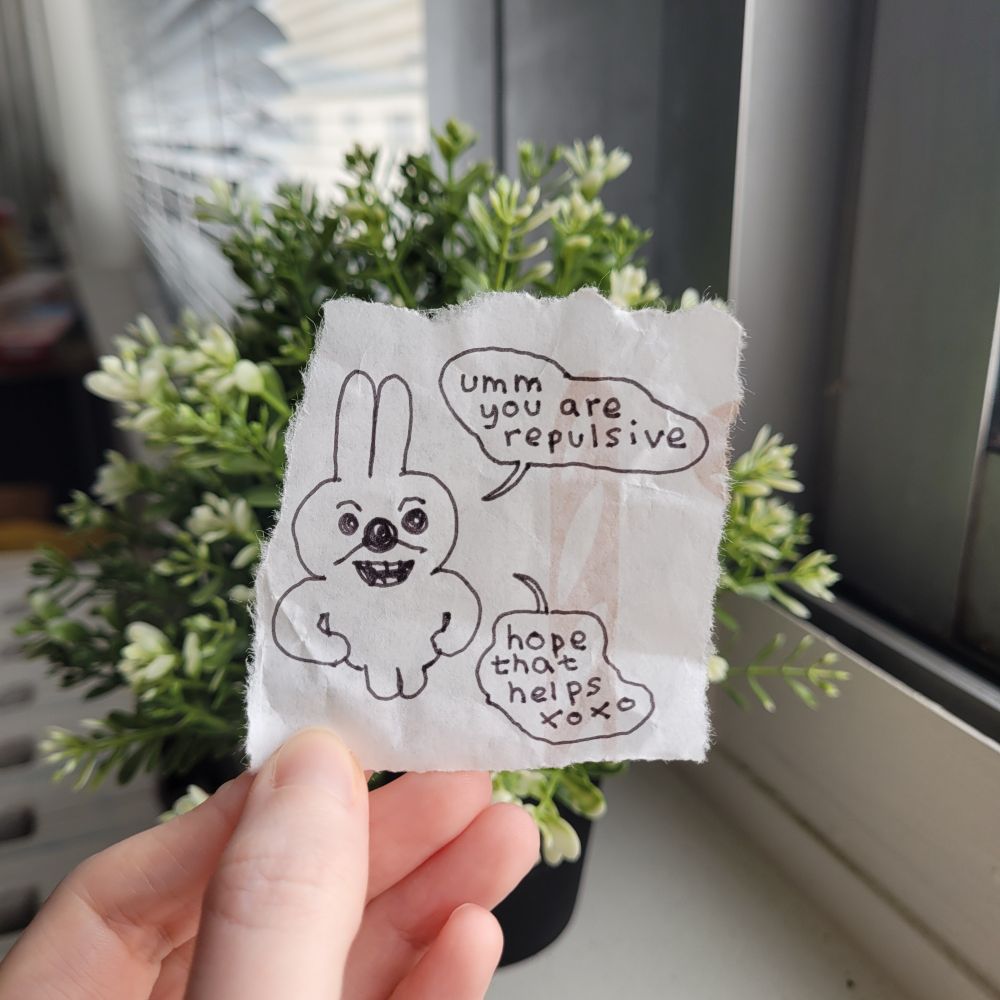 A photo of a torn scrap of paper with a grinning bunny drawn on it. The bunny says, "umm you are repulsive - hope that helps xoxo".