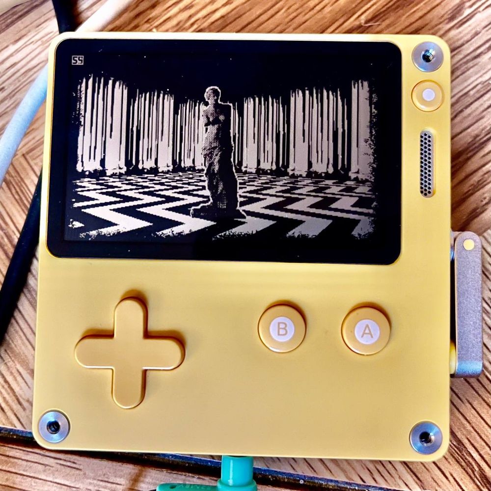 A photo of a PlayDate depicting a scene reminiscent of the red room from Twin Peaks. Venus de Milo stands in the center of a room with a white and black floor of zigzagging stripes, surrounded by curtains for walls.