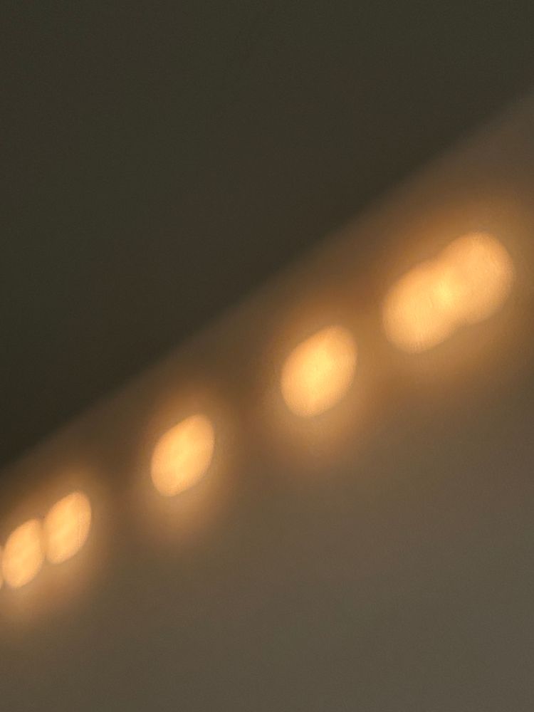 A white wall with orange orbs of sunlight on it. The person who took this picture is probably a vampire 